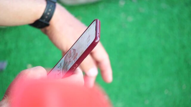 Hand smartphone scrolling, person using mobile phone apps outdoors on a vibrant green background