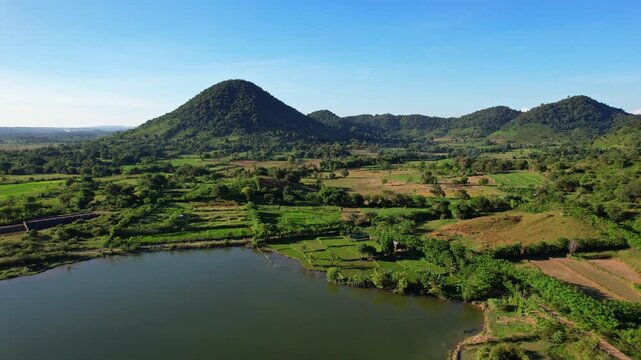 Aerial drone footage of the edge of Batu Bulan water reservoir lake, at early sunrise, in Sumbawa regency, Sumbawa island, Indonesia, with hill and farm lands around for corn crops