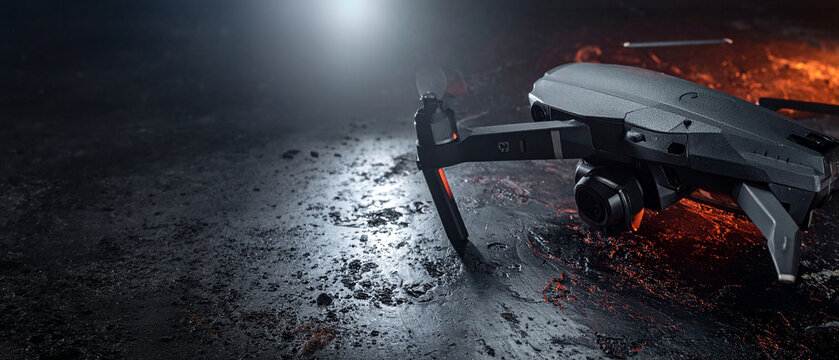 Modern quadcopter drone on textured black metallic ground. Cinematic spotlight with warm orange accent lighting. High resolution 3D render for technology, aerospace and surveillance industry themes.