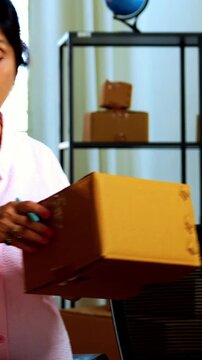 Indian senior couple doing E-commerce business from home, busy working in office managing online orders, packing parcels, dispatching boxes, taking customer calls and handling inventory together