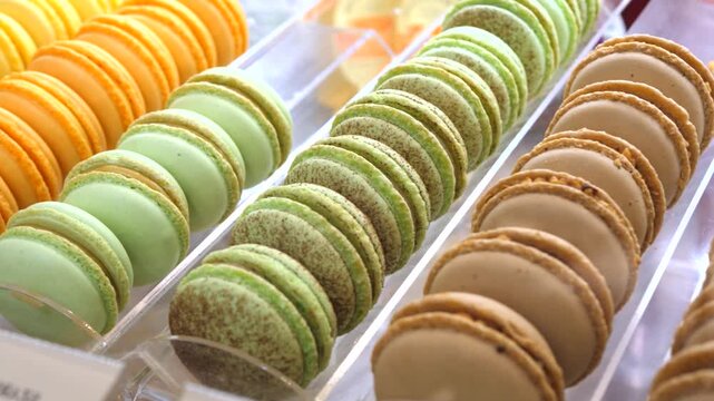 Delicious and colorful french macarons sitting in rows inside a bakery display case, showcasing various flavors like pistachio, chocolate, and coffee for sale at a local sweet patisserie