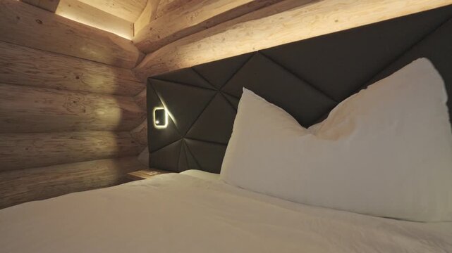 Cozy and modern hotel bedroom interior inside a rustic wooden log cabin with warm lighting