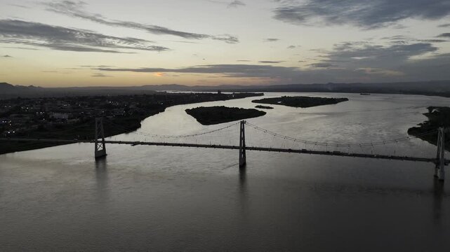 Drone hovers high over Zambezi River with wide view of Samora Machel Bridge just after sunset at twilight in Tete, Mozambique