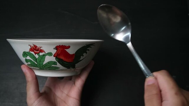Hand Tapping a Traditional Indonesian Rooster Bowl with a Spoon