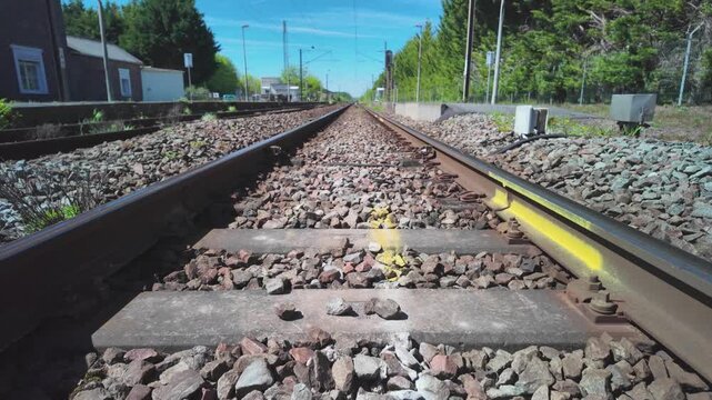 Railway track perspective transport travel tilt up shot through gravel and steel rails in sunny countryside environment
