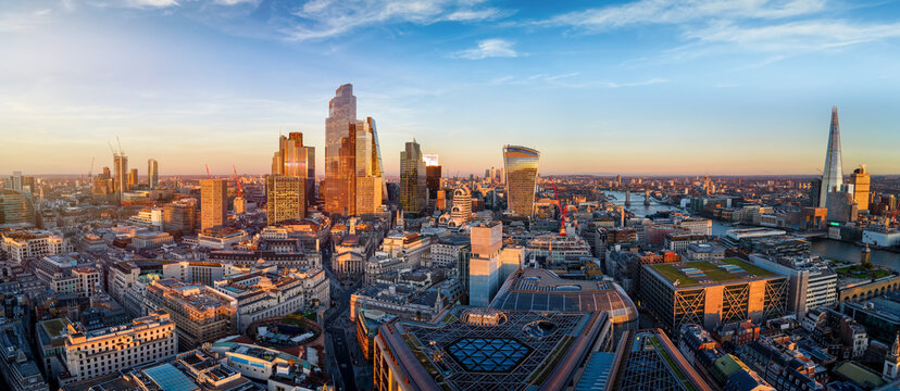 Panoramic aerial view of the skyline of London, England, skyline from the City until Tower Bridge with office skyscrapers reflecting the golden sunlight during sunset