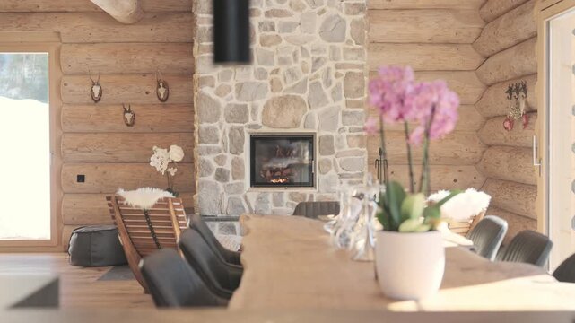 Warm and cozy interior of a mountain log cabin with a burning fireplace and wooden dining table