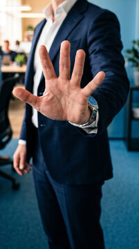 elegante uomo adulto in piedi in un ufficio che porge la mano in avanti col palmo aperto, fare segno di fermarsi, dare una scadenza