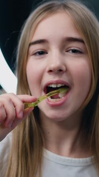 Good-looking 20 years old girl brushing teeth for morning routine and body care.in bathroom at home. Face portrait of happy young woman holding toothbrush brushing teeth looking in camera. Slow motion
