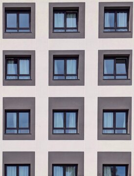 Fondo con vista de cerca de fachada sim&eacute;trica de hotel moderno con ventanas de cristal con marcos de metal, en muro liso