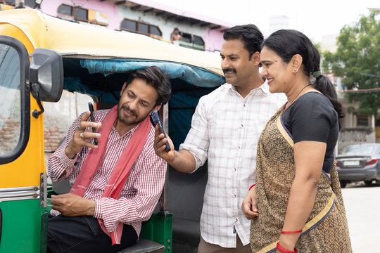 Indian couple making an online payment using app - payment bar code, bar code scanner, transportation, Delhi auto fare. Indian man using online payment using UPI - auto rickshaw driver