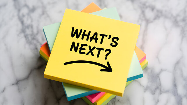 A stack of colorful sticky notes with a yellow note on top that says what's next