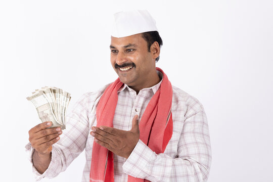 Portrait of young indian marathi man wearing white topi showing indian rupees against white background