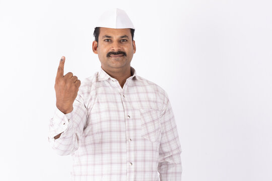 Portrait of a mid aged indian man in topi showing vote finger against white studio background
