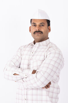 Portrait of smiling young indian farmer or rural man wearing topi looking at camera while standing on white background