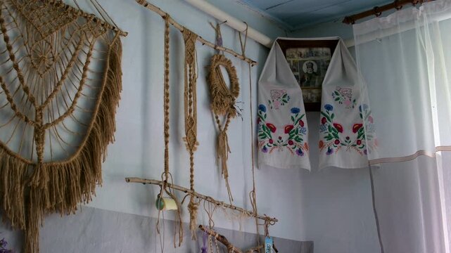 Corner of a traditional rural house with a religious icon decorated by an embroidered towel and wall macrame. Authentic handcrafted interior with warm cultural and village atmosphere.