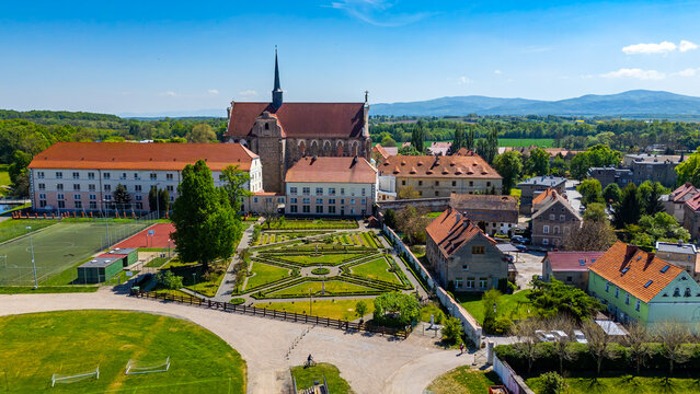 Aerial drone photograph of the Cistercian Monastery Complex in Henryk&oacute;w, Lower Silesia, featuring the Baroque church, a formal Italian geometric garden, monastery buildings, sports fields, and distant