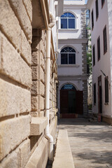 Fototapeta premium Narrow Alleyway Between Classic Buildings with Stone Walls and Arched Windows