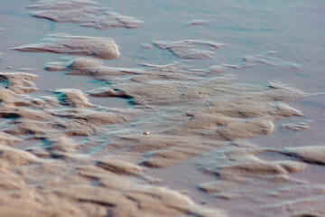 Naklejka premium Patterns in wet sand with small water pools on a coastal tidal flat.
