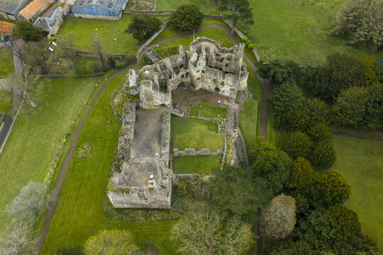 Aerial view of the medieval ruins of Dirleton Castle and Gardens surrounded by lush green lawns and mature trees in Dirleton, Scotland, United Kingdom.