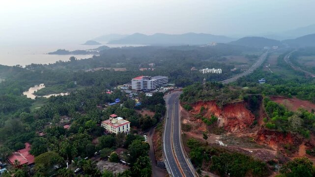 Drone shot capturing a long highway cutting across tropical landscapes, surrounded by palm-covered terrain, open plains, and rolling hills, creating a scenic coastal travel atmosphere.