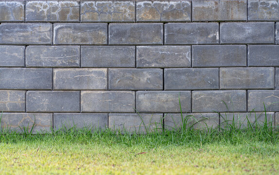 Several rows of a rough textured concrete block wall with Grass field.