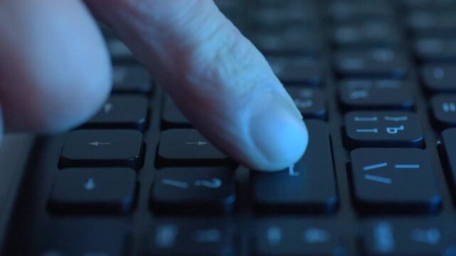 Closeup finger typing on backlit keyboard, remote work scene with IT technician entering commands, blue ambient light, laptop keys in shallow focus, fingertip pressing enter,