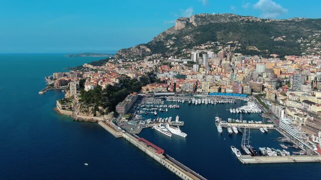 4K aerial view of the Rock of Monaco with Prince's Palace, Oceanographic Museum cliff edge, Port Hercule superyacht marina and T&ecirc;te de Chien rocky cliff above Mediterranean Sea.