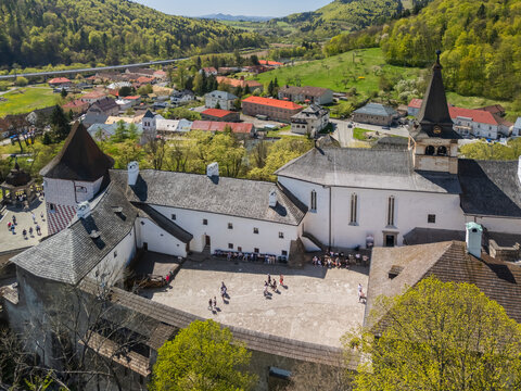 Aerial view of Orava Castle showing the inner courtyard with people, historic white stone buildings, and a tall tower overlooking the town in Dolny Kubin, Zilinsky kraj, Slovakia.