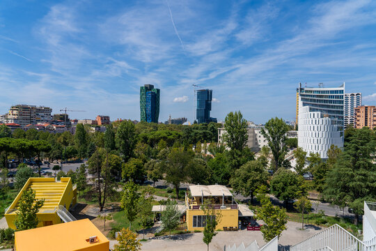 Tirana, Albania &mdash; August 20, 2025: Panoramic view of modern skyscrapers, including TID Tower, surrounded by lush green trees under a blue sky in the city center.