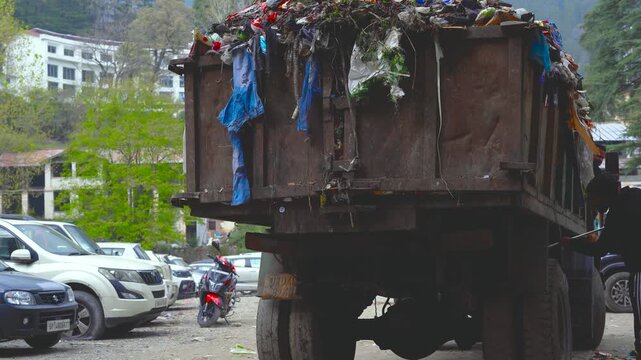Worker cleaning a municipal garbage truck in a parking area in Nainital, India