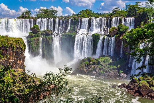 Majestic Iguazu Falls panoramic view with lush green tropical rainforest and blue sky, Misiones, Argentina