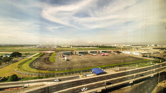 Manila, Philippines - May 15, 2025: View of Ninoy Aquino International Airport terminal and aircraft parking area in Manila with AirAsia airplanes, taxiways and urban skyline under sunny sky.