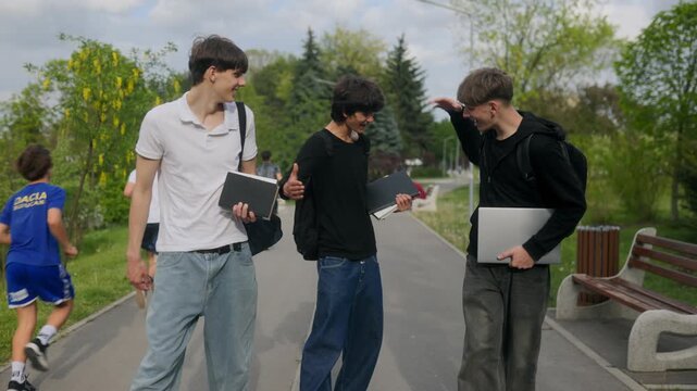 Happy Teen Male Students Walking and Laughing with Handshake in Park