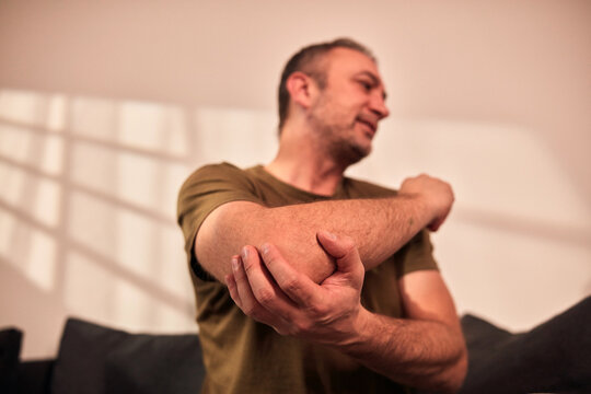 Man with elbow and arm pain at home.