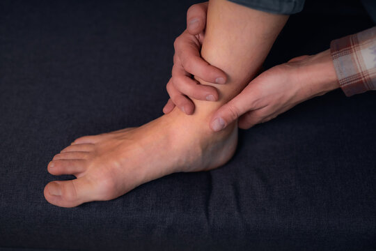 Man at home holding painful injured foot.