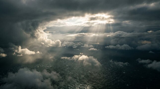 Dramatic aerial overhead shot capturing sun rays piercing through dark storm clouds over a vast, turbulent ocean, showcasing nature's powerful beauty and atmospheric intensity