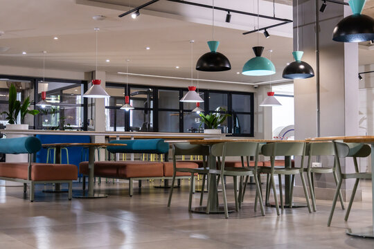 Communal dining area featuring long wooden table with rust teal benches and muted green chairs