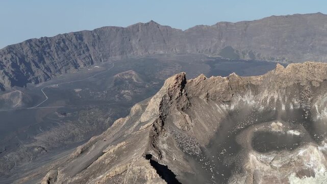 Aerial drone view from the rim of Pico do Fogo crater, revealing the expansive volcanic plains of Ch&atilde; das Caldeiras and the dramatic Bordeira wall in Cabo Verde