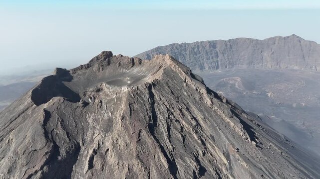 Aerial drone shot of Pico do Fogo volcano summit and its main crater in Cape Verde. Cinematic view of the rugged volcanic peak and caldera landscape in Ch&atilde; das Caldeiras, Fogo Island