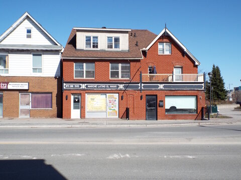 Gatineau, Quebec, Canada &ndash; April 18, 2026: A red brick building features the "March&eacute; Latino El Man&aacute;" grocery storefront and a second-story residential balcony at 194 Bd Saint-Joseph.