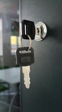 Vertical close-up of keys in a glass door lock. Concept of commercial real estate rental, office security, business access and property leasing. Lock and keу.