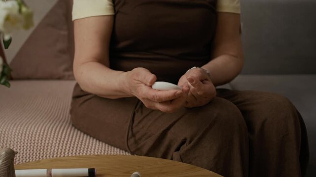 Midsection close up shot of adult woman taking finger prick blood sample for glucometer while controlling blood sugar levels during everyday diabetes care at home