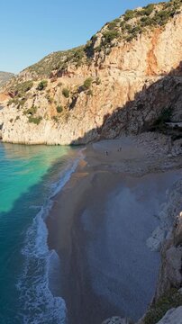 A couple experiences the breathtaking beauty of Kas in Antalya, Turkey. Relax on serene beaches and enjoy the crystal-clear waters under the warm sun. Kaputas Beach is perfect for a summer getaway.