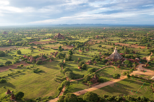 Aerial view of ancient Buddhist temples and pagodas scattered across lush green plains under a soft morning sky Old Bagan, Mandalay Region, Myanmar Burma.