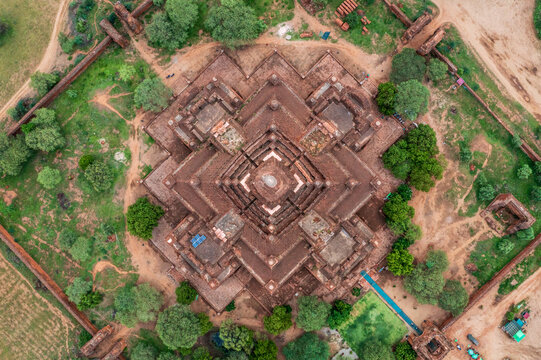 Aerial view of the symmetrical brick architecture of Dhammayangyi Temple surrounded by lush green trees and ancient walls in Old Bagan, Mandalay Region, Myanmar Burma.