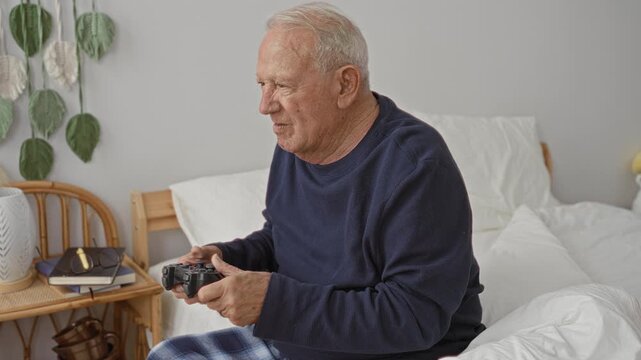 Man holding a game controller raises both arms while seated on a bed in a bedroom, expressive motion and shifting posture captured; surprise play.