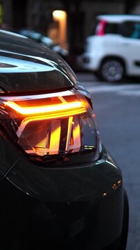 Vertical: A front car blinker flashes repeatedly in the dark, revealing a car parked in a restricted area. Urban stillness meets the bright pulse of an overlooked rule.