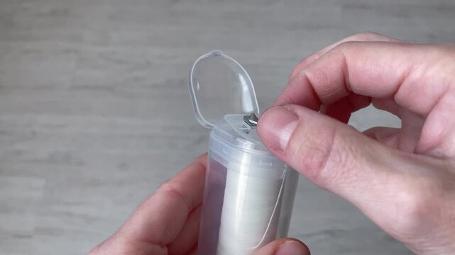 The woman opens the box and pulls out the dental floss. The concept of effectively removing bacteria in hard-to-reach places, healthy gums, fresh breath and maintaining a beautiful smile. Close up