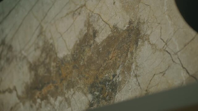 Close view shows marble surface with natural veins and brown patch in center, texture looks rough yet elegant, colors blend softly creating calm and organic feel
